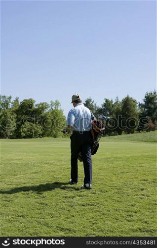 Rear view of a man carrying a golf bag