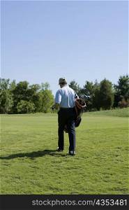 Rear view of a man carrying a golf bag