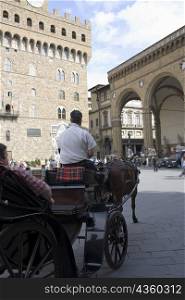 Rear view of a man driving a horsedrawn carriage, Portico of the Lansquenetes, Florence, Italy