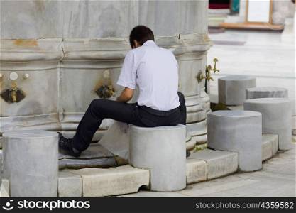 Rear view of a man filling a bag with water from a faucet, Istanbul, Turkey