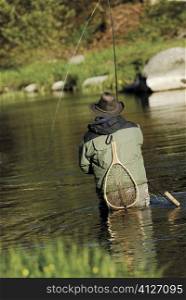 Rear view of a man fishing in the river