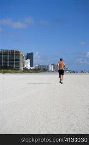 Rear view of a man jogging on the beach, South Beach, Miami Beach, Florida, USA