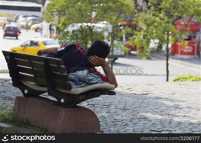Rear view of a man lying on a park bench, Istanbul, Turkey