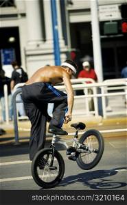 Rear view of a man performing tricks on a cycle, San Francisco, California, USA