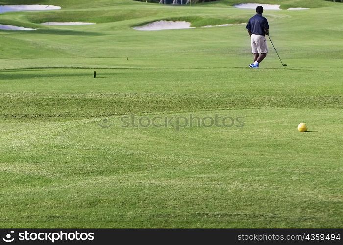 Rear view of a man playing golf in a golf course