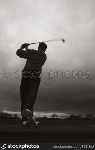 Rear view of a man playing golf on a golf course