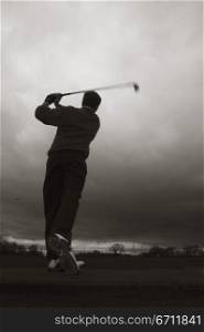 Rear view of a man playing golf on a golf course