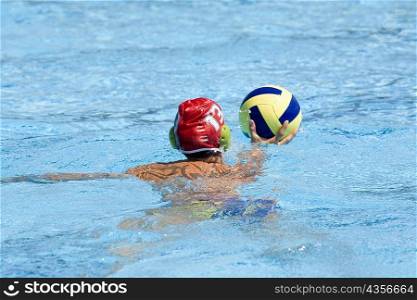 Rear view of a man playing water polo in a swimming pool