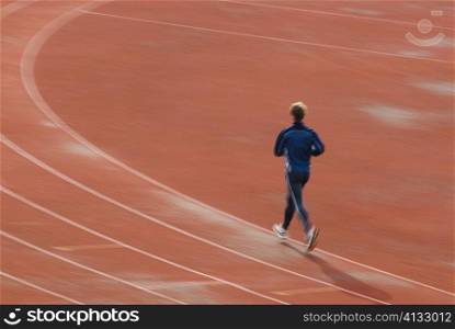 Rear view of a man running on a sports track
