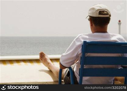 Rear view of a man sitting in an armchair on the beach, Baie De Cannes, Provence-Alpes-Cote D&acute;Azur, France