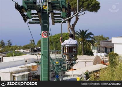 Rear view of a man sitting in an overhead cable car, Capri, Campania, Italy