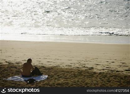 Rear view of a man sitting on the beach, Grande Plage, Biarritz, France