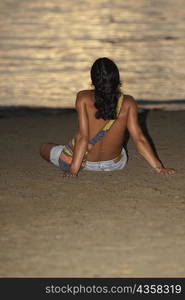 Rear view of a man sitting on the beach, Taganga Bay, Departamento De Magdalena, Colombia