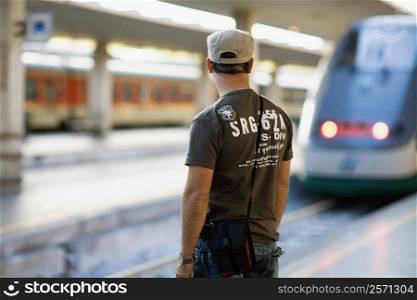 Rear view of a man standing at a railroad station, Rome, Italy