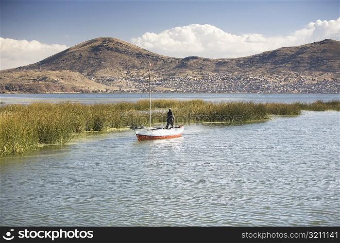 Rear view of a man standing on a boat in a lake, Lake Titicaca, Puno, Peru