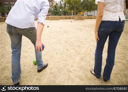 Rear view of a man throwing a ball with a woman standing beside him