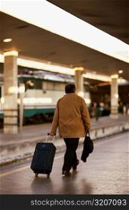Rear view of a man walking at a railroad station platform, Rome, Italy