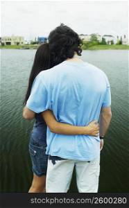 Rear view of a man with a woman standing at a lake