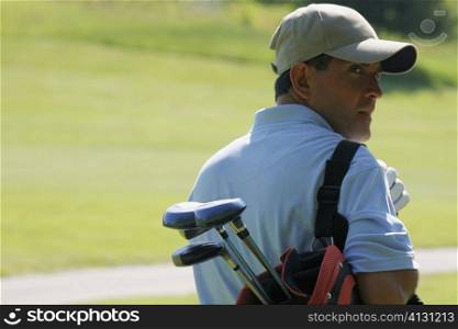 Rear view of a mature man carrying a golf bag