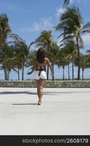 Rear view of a mature woman walking on the beach, South Beach, Miami Beach, Florida, USA