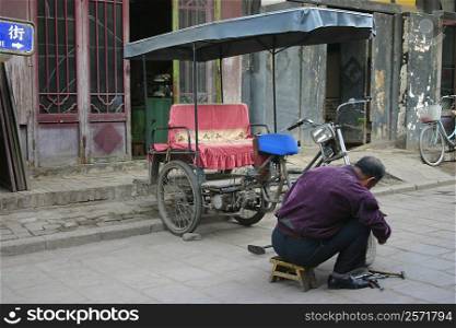 Rear view of a mechanic repairing a pedicab, Pingyao, Shaanxi Province, China