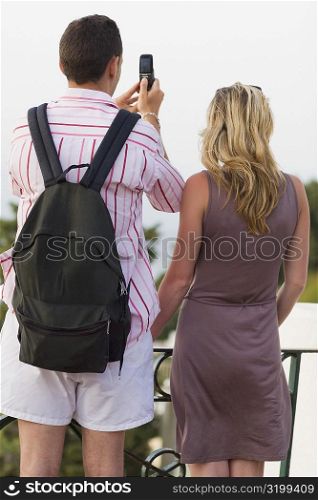 Rear view of a mid adult couple taking photographs with a mobile phone, Capri, campania, Italy
