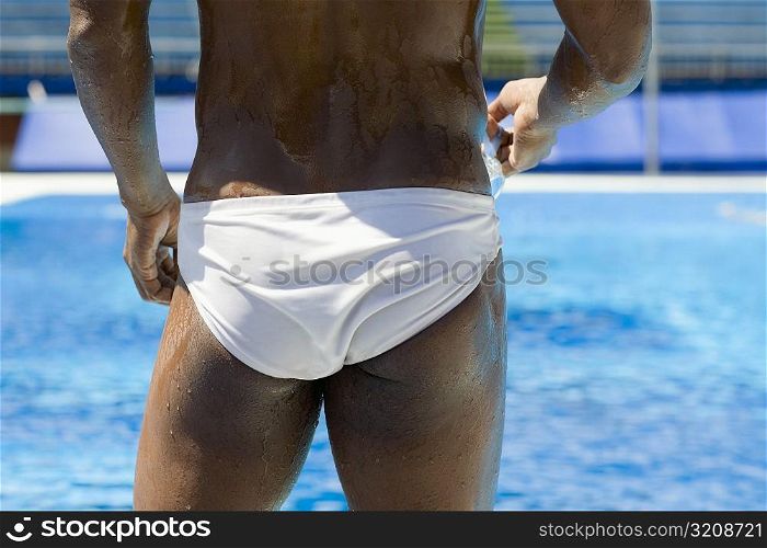 Rear view of a mid adult man holding swimming goggles