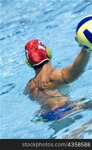 Rear view of a mid adult man playing water polo in a swimming pool