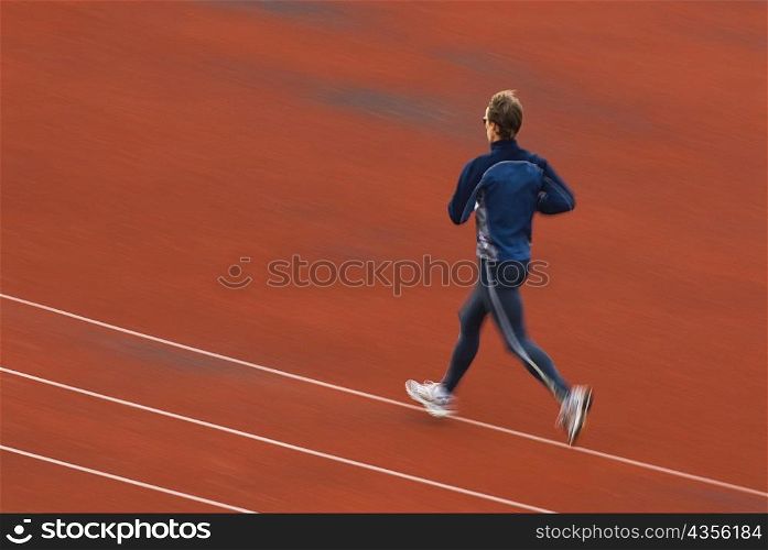 Rear view of a mid adult man running on a running track