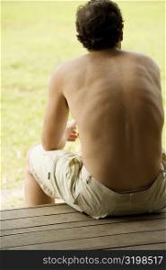 Rear view of a mid adult man sitting on a bench