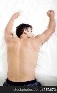 Rear view of a mid adult man sleeping on a bed