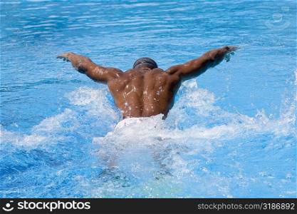 Rear view of a mid adult man swimming in a swimming pool