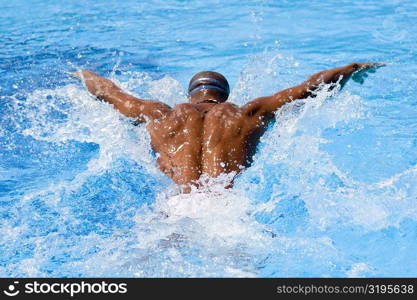 Rear view of a mid adult man swimming the butterfly stroke in a swimming pool