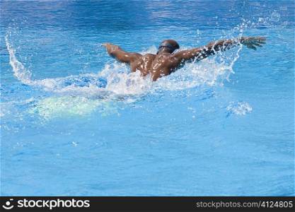 Rear view of a mid adult man swimming the butterfly stroke in a swimming pool