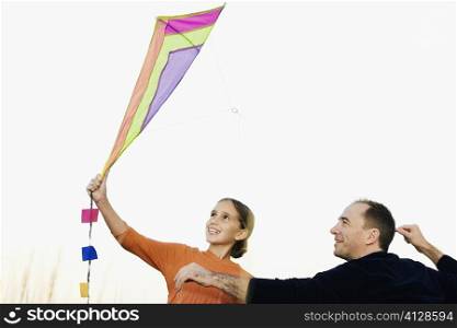 Rear view of a mid adult man with his daughter flying a kite