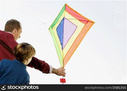 Rear view of a mid adult man with his son flying a kite