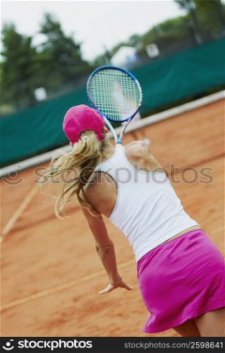 Rear view of a mid adult woman playing tennis with another person