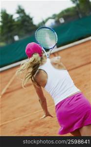 Rear view of a mid adult woman playing tennis with another person