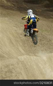 Rear view of a motocross rider performing jump on a motorcycle