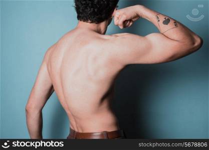 Rear view of a muscular young man flexing his arm