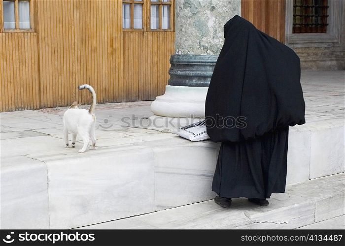 Rear view of a Muslim woman in hijab standing with a cat, Istanbul, Turkey