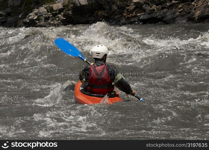 Rear view of a person kayaking in a river