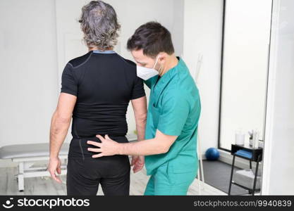 Rear view of a physiotherapist examining man back. High quality photo. Rear view of a physiotherapist examining man back.