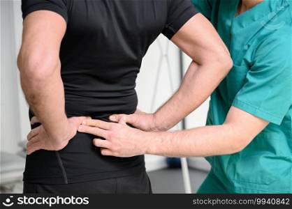Rear view of a physiotherapist examining man back. High quality photo. Rear view of a physiotherapist examining man back.
