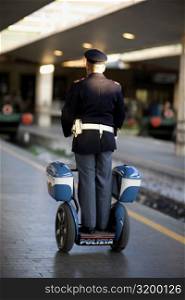 Rear view of a policeman on a scooter at a railroad station platform, Rome, Italy