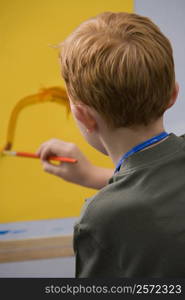 Rear view of a schoolboy painting in an art class