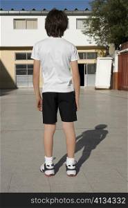 Rear view of a schoolboy standing in front of a school building