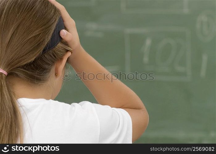Rear view of a schoolgirl with her hands on her head