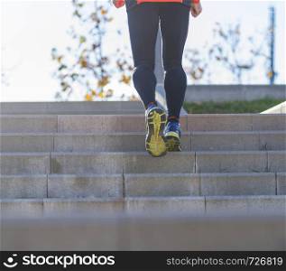 Rear view of a senior caucasian athlete man training running up and down the stairs outdoors in a park in a sunny day