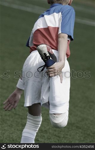 Rear view of a soccer player stretching his leg